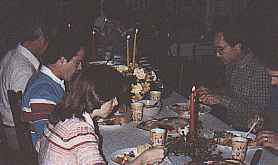 <Family sitting at the table eating food.>