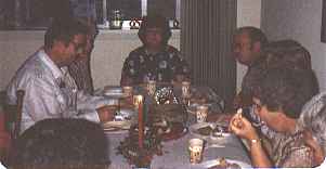 <Family sitting at the table eating food.>